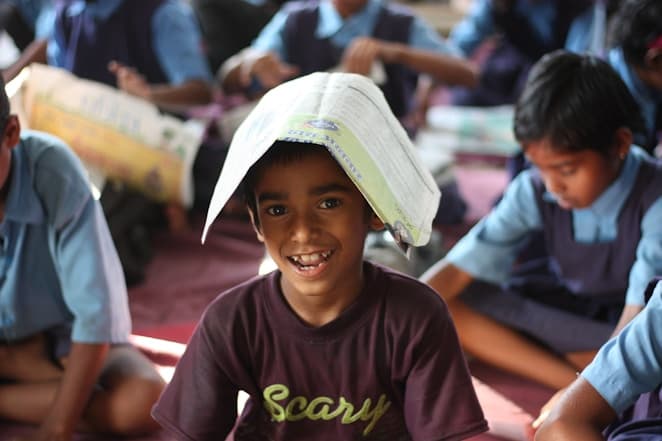 A boy laughing with a book on his head