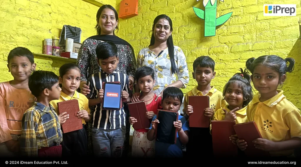 Photo of students in the yellow room displaying tablets from digital libraries set up by iDream Education in partnership with Sarthak Foundation