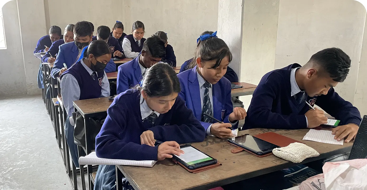 Students taking an assessment on learning tablets which are one of the educational impact assessment tools for NGO working for education