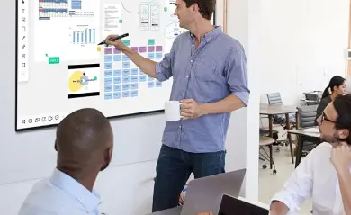 Teacher using a smart board interactive flat panel 65 inch to teach students in a classroom