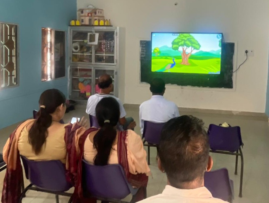 Teachers watching an educational video on a Smart TV in a remote school